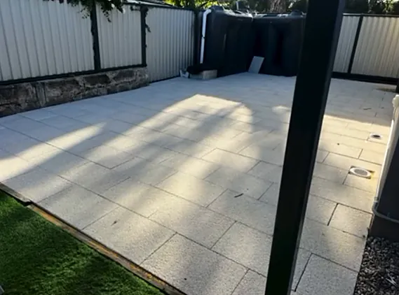 Backyard after, one large area of pale square pavers meeting the lawn