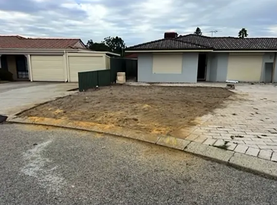 Front yard of bare dirt next to a paved driveway