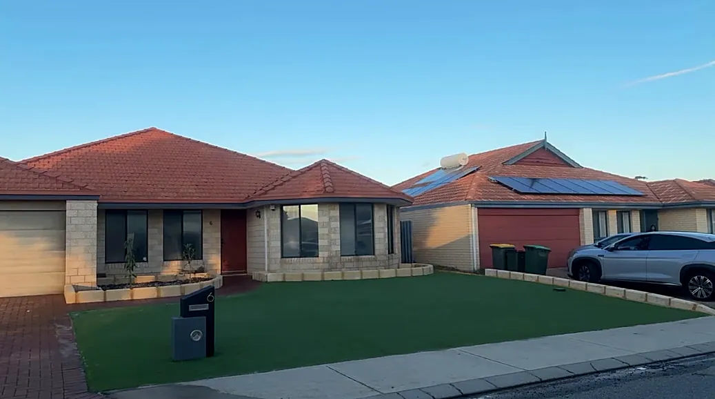 Same front yard after, with an even green lawn and neat garden beds along the house