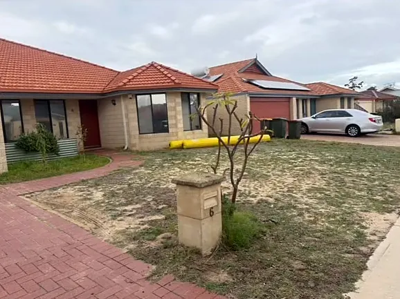 Front yard before, with dry patchy lawn, bare sand and an old letterbox