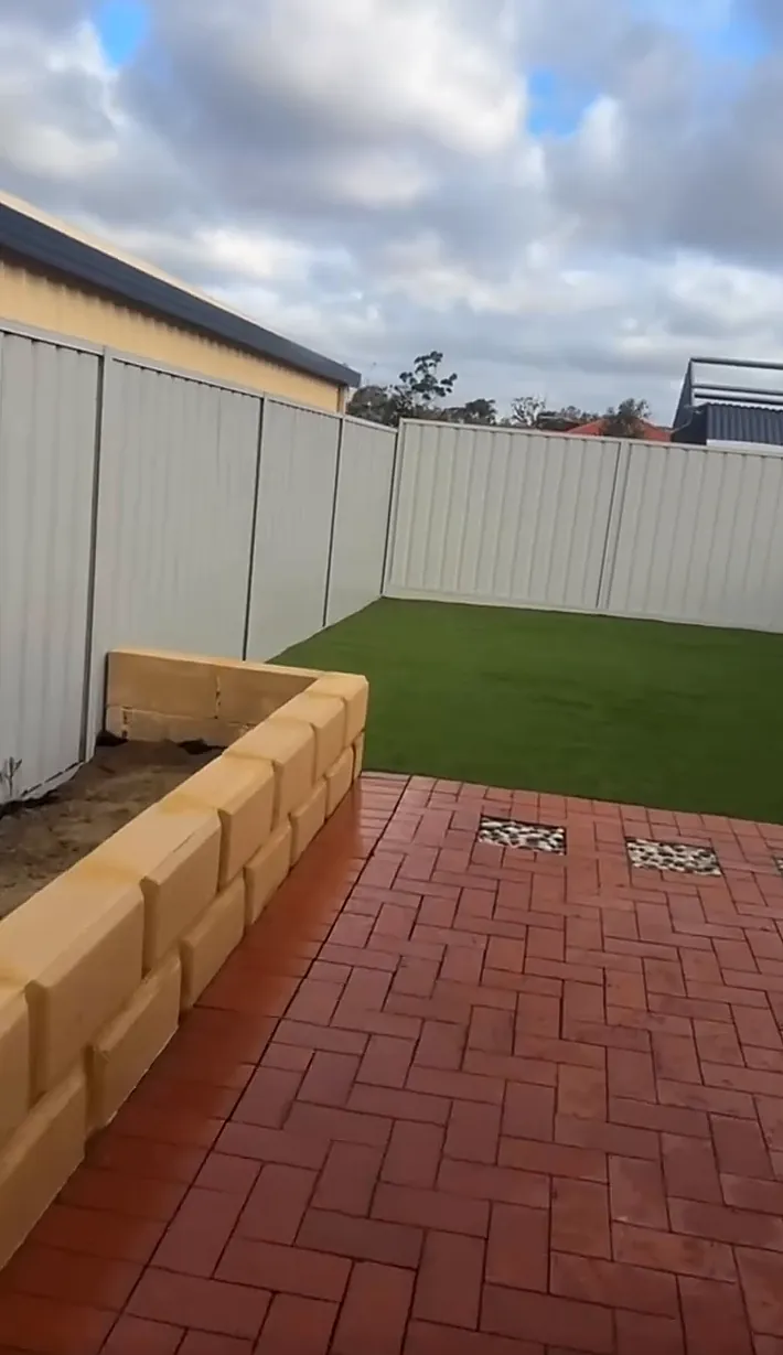New raised garden bed built from limestone blocks, with fresh lawn beyond