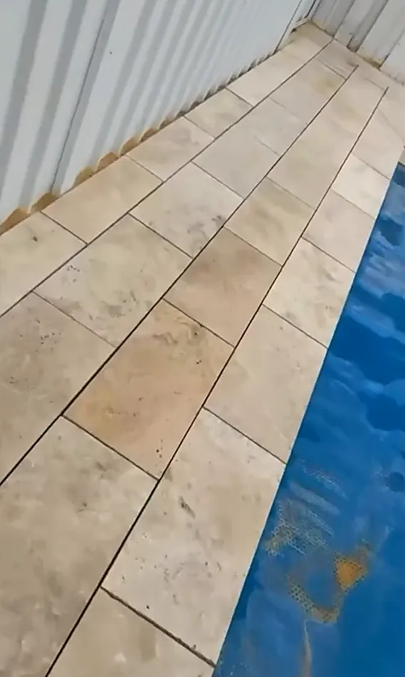 Close view of pale stone coping laid along the edge of a pool