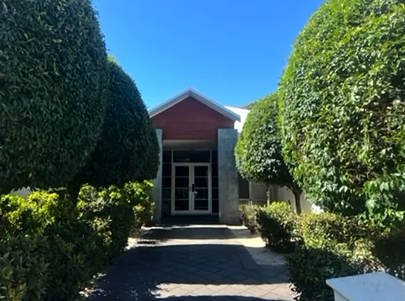 Rounded topiary hedges framing a paved path to a front door